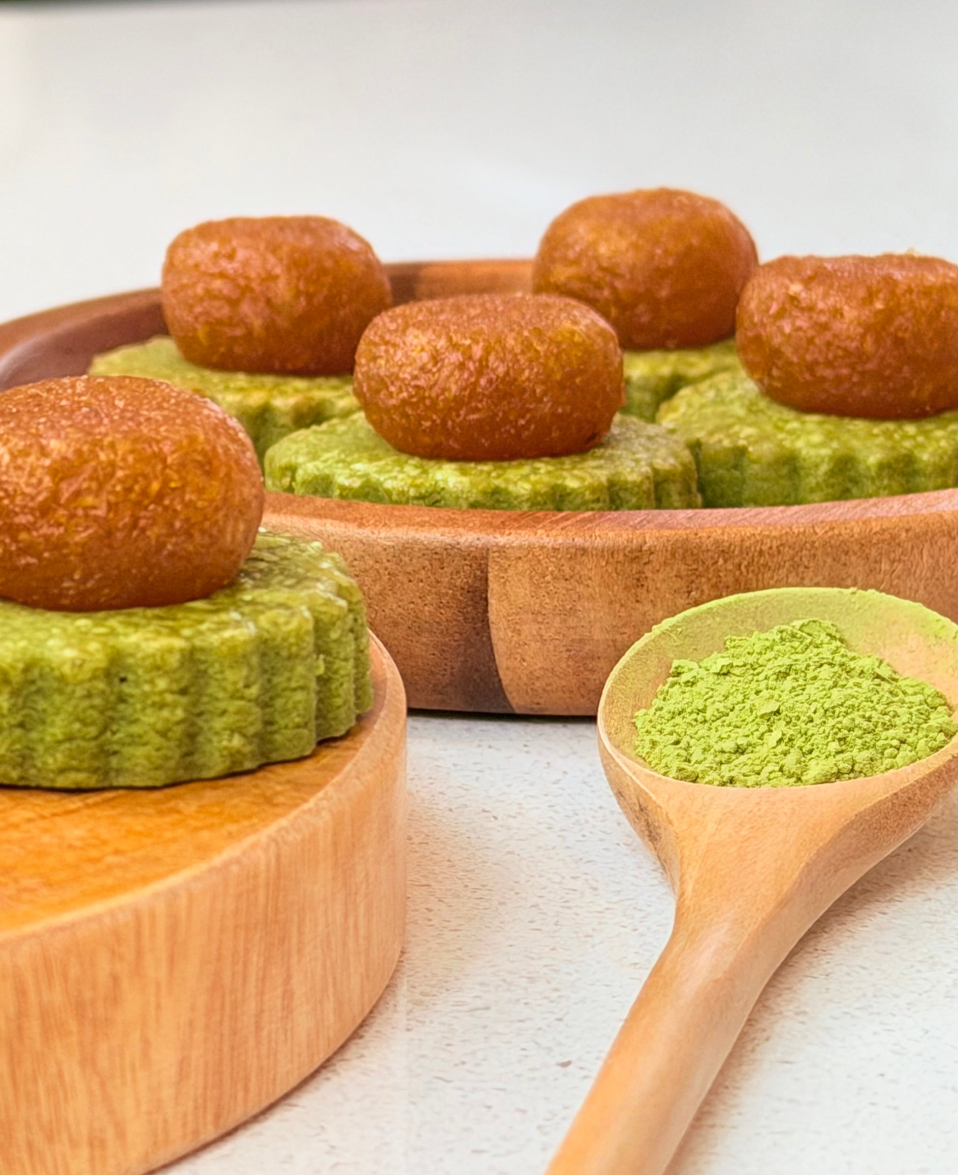Matcha pineapple tarts with a wooden spoon filled with premium match powder on a light background