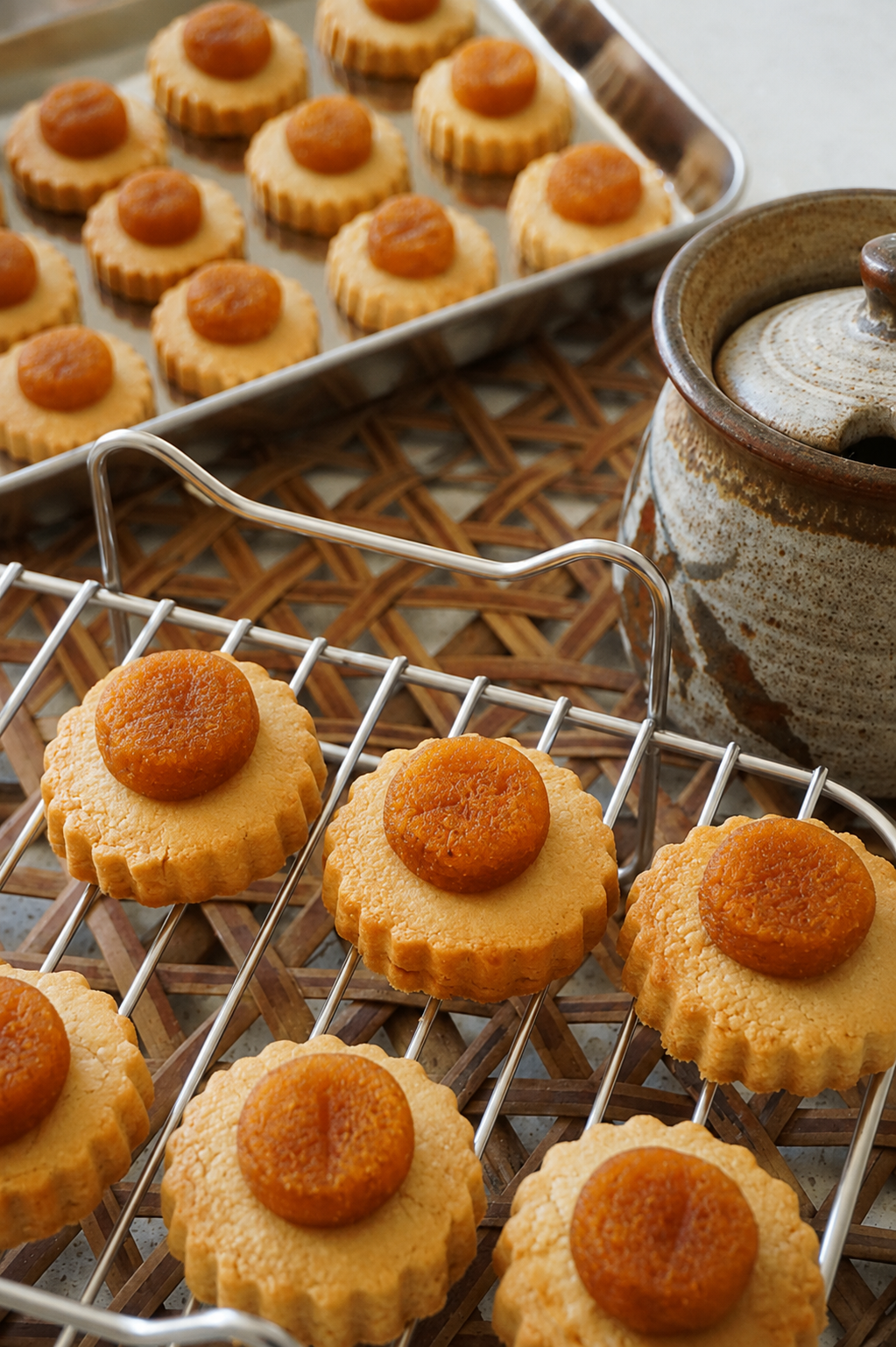 Pineapple tarts sitting on a rack next to a pot of tea.
