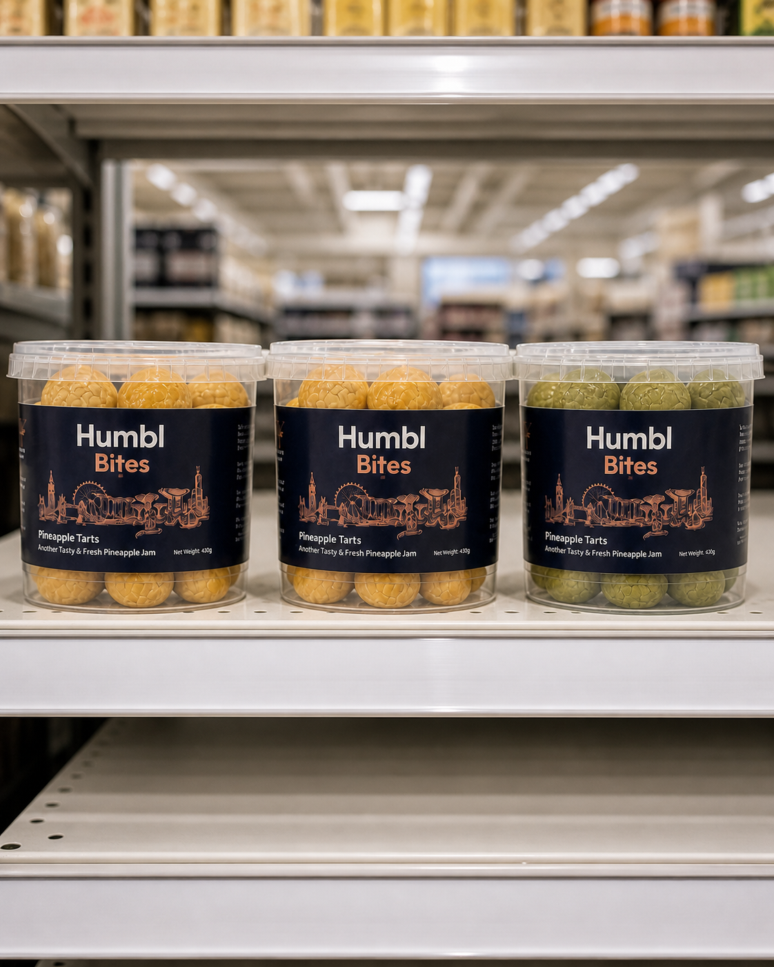 Three clear plastic tubs of Humbl Bites Pineapple Tarts displayed on a white store shelf. The center tub contains the classic version, and the right tub contains Matcha pineapple tarts.